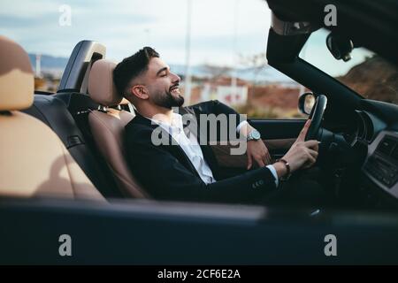 Side view of businessman driving a car at the sunset Stock Photo