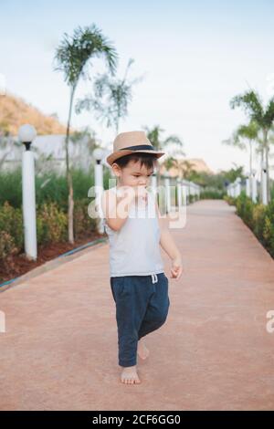 Ethnic kid walking barefoot in street Stock Photo