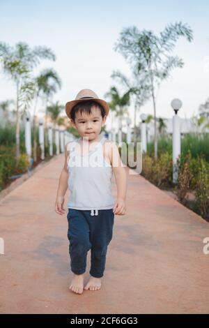 Ethnic kid walking barefoot in street Stock Photo
