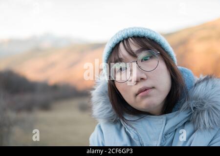 Asian Woman sitting resting in nature contemplating beautiful mountain landscape during hiking Stock Photo