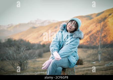 Asian Woman sitting resting in nature contemplating beautiful mountain landscape during hiking Stock Photo