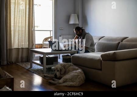 Stylish guitarist on couch in living room Stock Photo