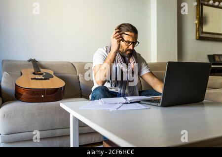 Contemporary man browsing devices in living room Stock Photo