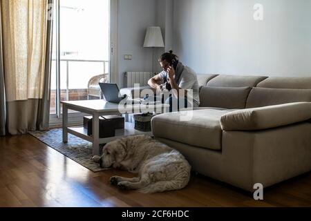 Young male musician calling on smartphone in living room Stock Photo