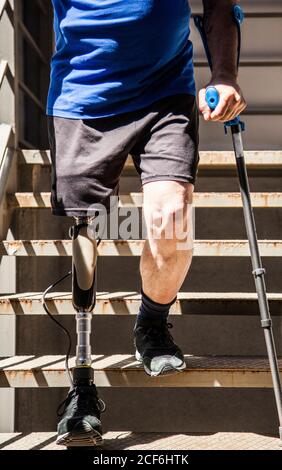 unrecognizable man amputated with crutches testing his new leg prosthesis going down stairs Stock Photo