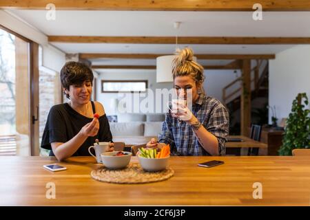 Two beautiful and young women having breakfast at home and having fun Stock Photo