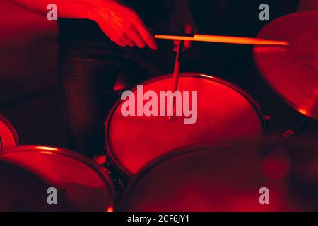 anonymous male holding drumsticks and playing on drums in redness Stock Photo