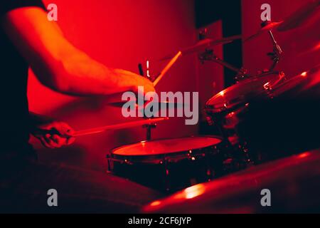 anonymous male holding drumsticks and playing on drums in redness Stock Photo
