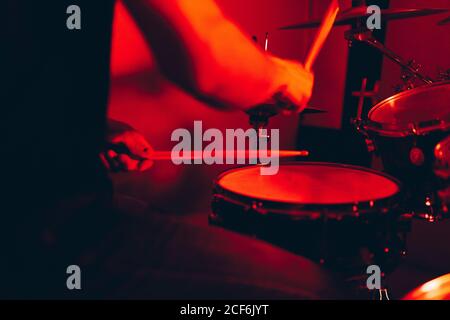anonymous male holding drumsticks and playing on drums in redness Stock Photo