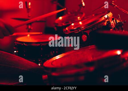 anonymous male holding drumsticks and playing on drums in redness Stock Photo