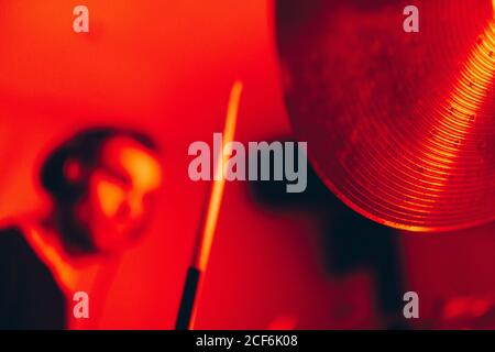 Side view of crop male holding drumsticks and playing on drums in redness Stock Photo