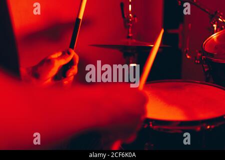 anonymous male holding drumsticks and playing on drums in redness Stock Photo