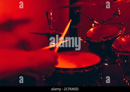 anonymous male holding drumsticks and playing on drums in redness Stock Photo