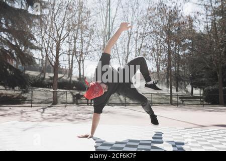 Young athletic guy practicing break dance in park in sunny weather Stock Photo