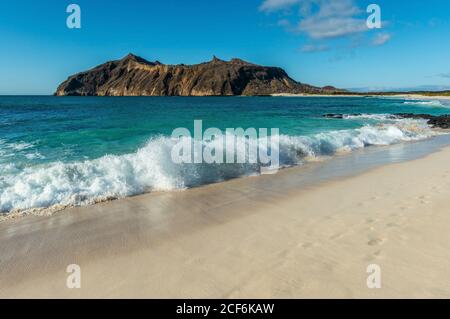 Landscape of strong waves by the beach in Stephens Bay with Witch Hill in the background, San Cristobal island, Galapagos, Ecuador. Stock Photo