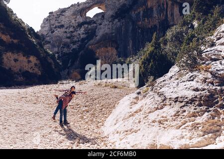 Young couple playing in canyon between rock mountains in sunny day Stock Photo
