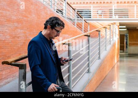 Aged man standing with baggage and talking on smartphone Stock Photo