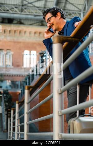 Aged man standing with baggage and talking on smartphone Stock Photo
