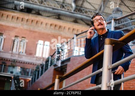 Aged man standing with baggage and talking on smartphone Stock Photo