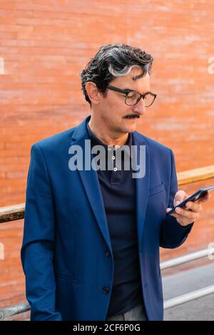 Senior businessman in blue jacket using smartphone Stock Photo