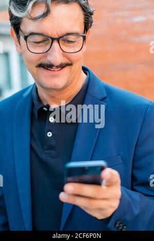 Senior businessman in blue jacket using smartphone Stock Photo