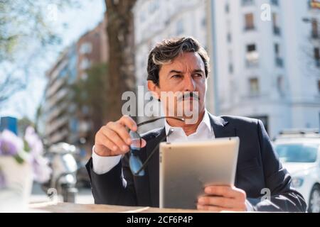 Elderly man using gadget while relaxing at cafe Stock Photo