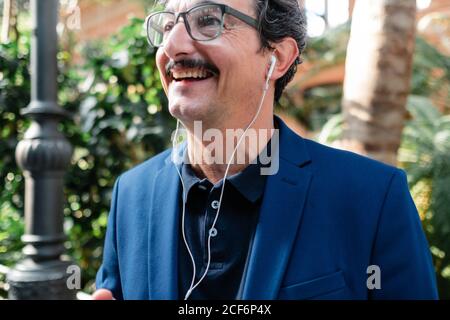 Aged businessman using smartphone with headphones and smiling Stock Photo