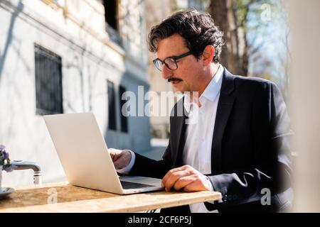 Elderly man using gadget while relaxing at cafe Stock Photo