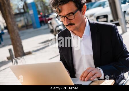 Elderly man using gadget while relaxing at cafe Stock Photo