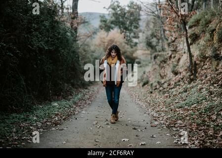Attractive Woman in warm jacket walking in autumn forest and enjoying landscape Stock Photo