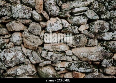 Old gray stones covered with moss and stacked in construction Stock Photo