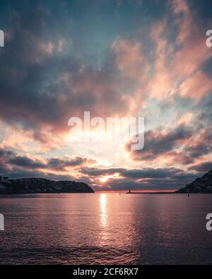 Clouds floating on sundown sky over rippling sea water and coast of Mallorca Island in evening in Spain Stock Photo