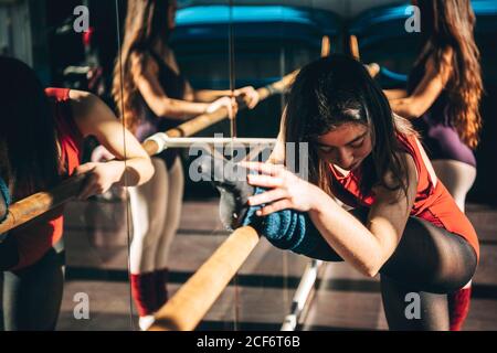 Concentrated ballet dancers training with barre in front of mirror in studio. Stock Photo