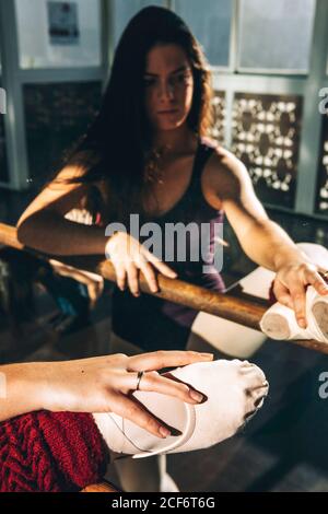 Concentrated Woman in pointe shoes warming up with barre in front of mirror. Stock Photo