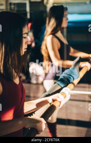 Young ballerinas training in sunny studio standing near mirror with barre. Stock Photo