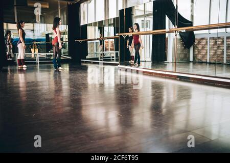 Two young ballerinas in front of big wall mirror training together in studio. Stock Photo