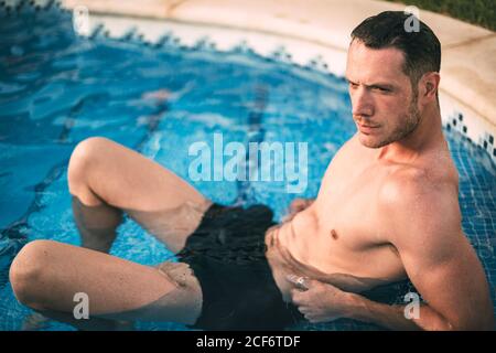 man lying on steps in pool Stock Photo