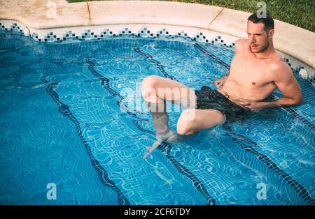 man lying on steps in pool Stock Photo