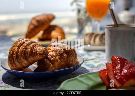 Homemade full brunch breakfast in sunlight with croissants, strawberries, tea or coffee and orange juice Stock Photo