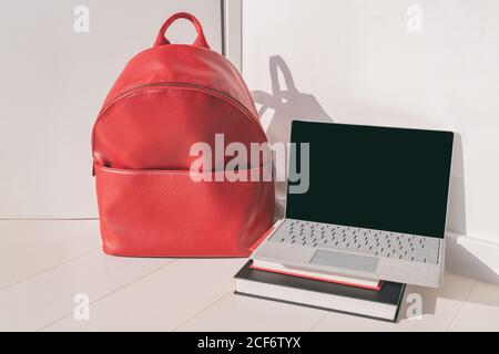 Back to school online classes laptop and red backpack bag with study books, university or college student Stock Photo