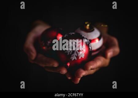 Closeup anonymous person demonstrating handful of decorated Christmas balls against black background Stock Photo