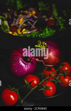 Healthy vegan food with fresh lettuce, cherries tomatoes, red onion and corn on dark background Stock Photo