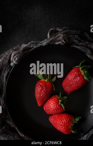 Red and fresh strawberries flat lay in black dish Stock Photo