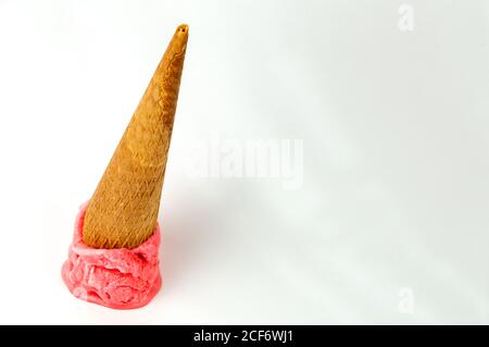 Waffle cone with bright strawberry ice cream scoop fallen on white background Stock Photo