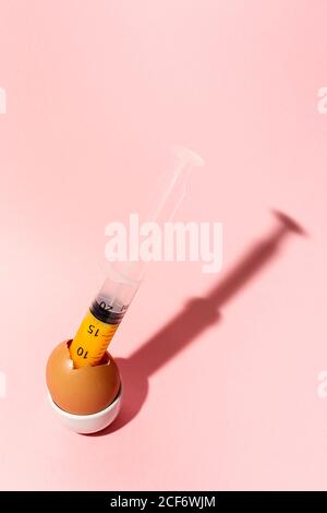 Egg with syringe in eggcup Stock Photo