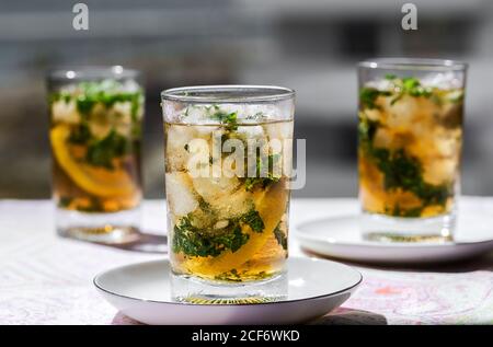 Glasses of cold refreshing tea with ice cubes and lemon slices placed on table in cafe Stock Photo
