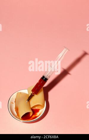 From above cannelloni stuffed with tomato sauce by syringe and served on small plate on pink background Stock Photo