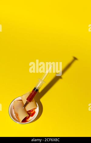 From above cannelloni stuffed with tomato sauce by syringe and served on small plate on yellow background Stock Photo