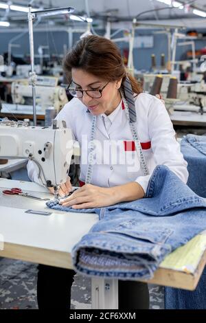 Working Woman hands in textile factory sewing on industrial sewing ...