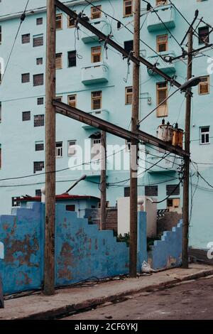 Empty asphalt road along blue rocked fence joint poles and blue residential building on background in Cuba Stock Photo
